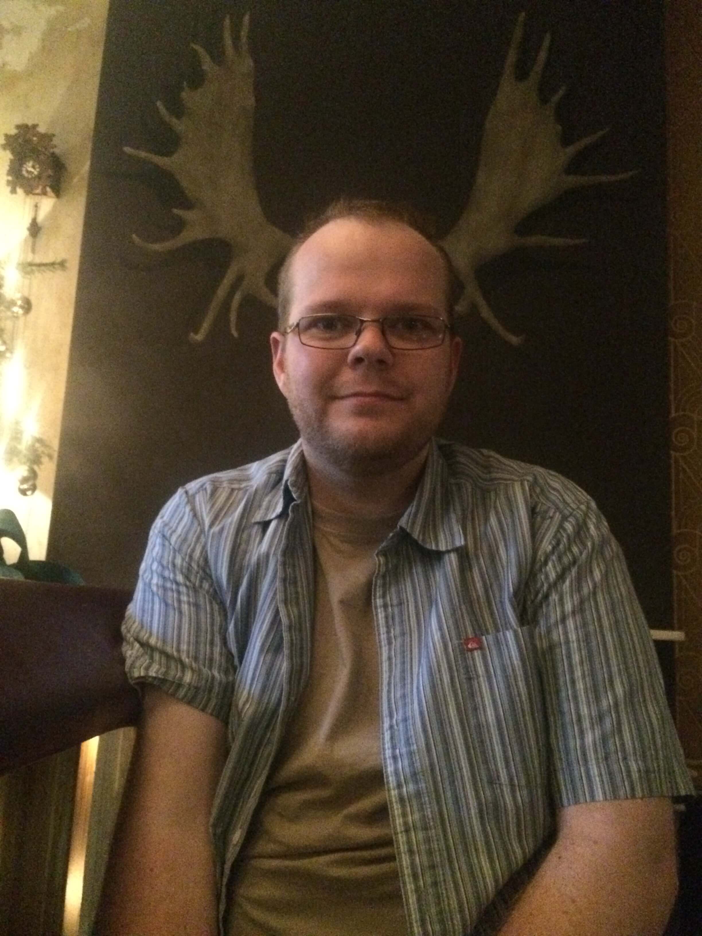 Ru sat at a bar with mounted moose antlers lined up perfectly behind his head, at a work Christmas party at a previous job.